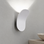 Black curved wall sconce casting cool light in a minimalist interior.