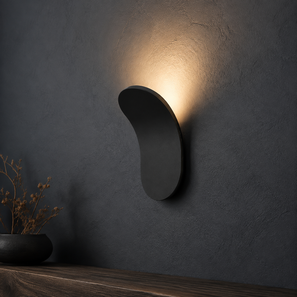 Champagne curved wall sconce casting cool light on a pale stone wall.