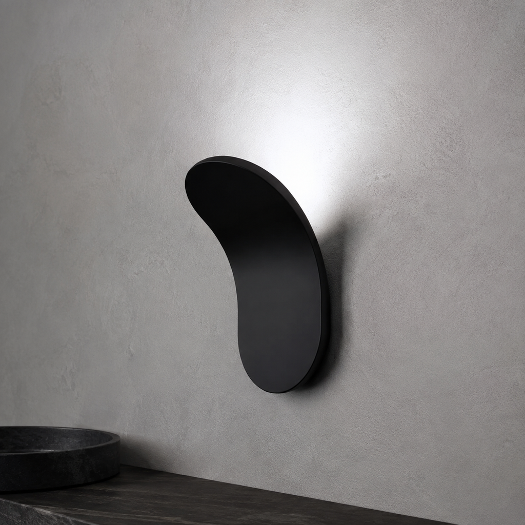 Gold curved wall sconce casting warm light above a dark wood surface.