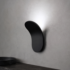 Gold curved wall sconce casting warm light above a dark wood surface.