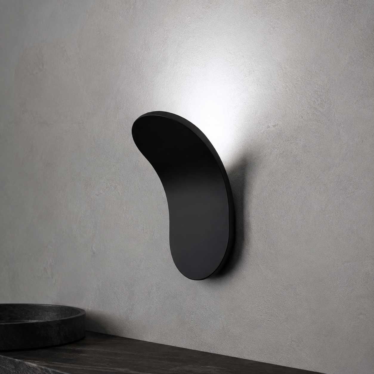 Gold curved wall sconce casting warm light above a dark wood surface.