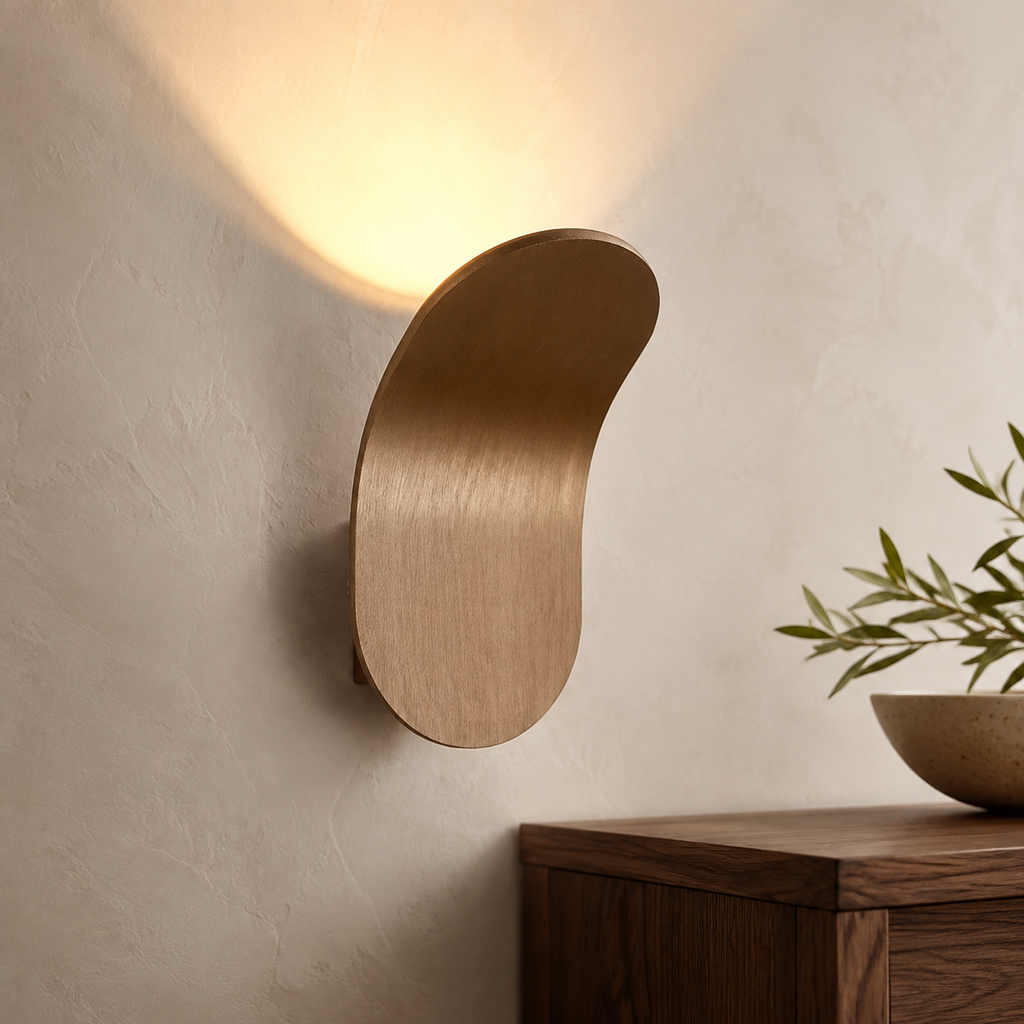 Champagne curved wall sconce casting warm light above a walnut console.