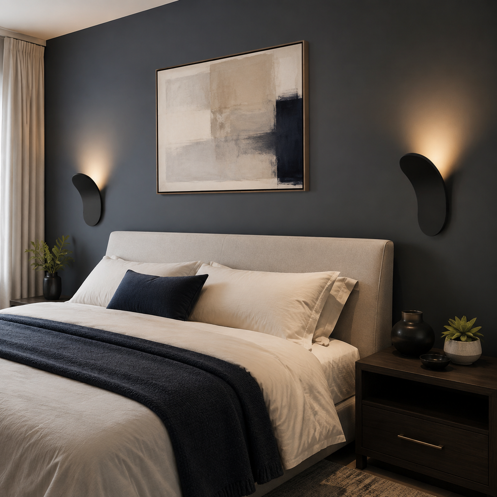 Black curved wall sconce casting warm light on a charcoal bedroom wall.