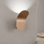 White curved wall sconce casting warm light beside a neutral console.