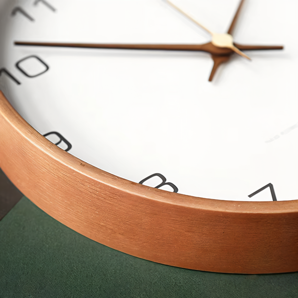Close detail of the wood rim and hands on a white wall clock