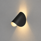 Black wall lamp mounted on a light gray wall, casting warm light upward and downward.