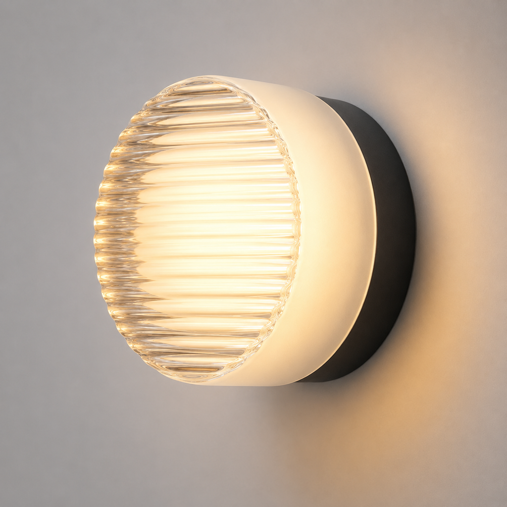 Round ribbed acrylic LED wall lamp glowing warm white with a black mounting base against a neutral wall.