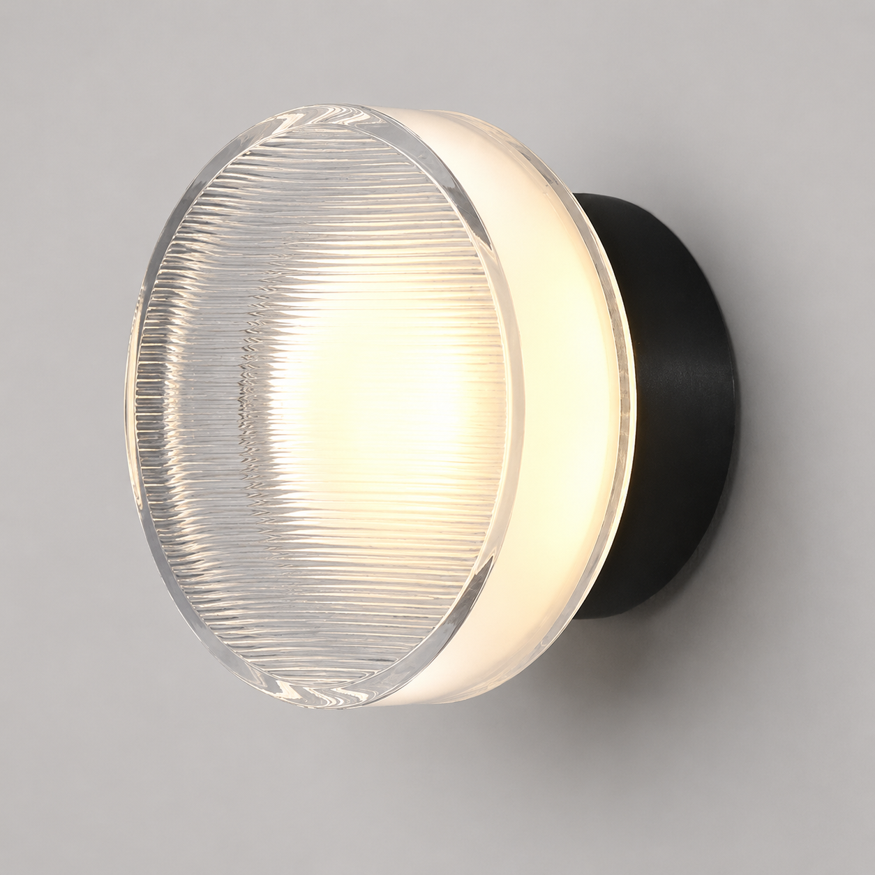 Round ribbed acrylic LED wall lamp glowing warm white with a black mounting base against a neutral wall.