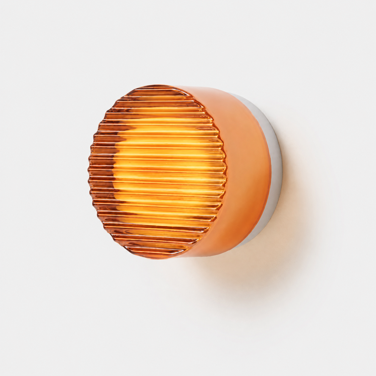 Orange ribbed acrylic LED wall lamp glowing warm white against a white wall.