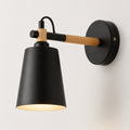 Scandinavian cone LED wall lamp with a solid wood arm, glowing warm white against a neutral wall.