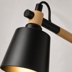 Scandinavian cone LED wall lamp with a solid wood arm, glowing warm white against a neutral wall.