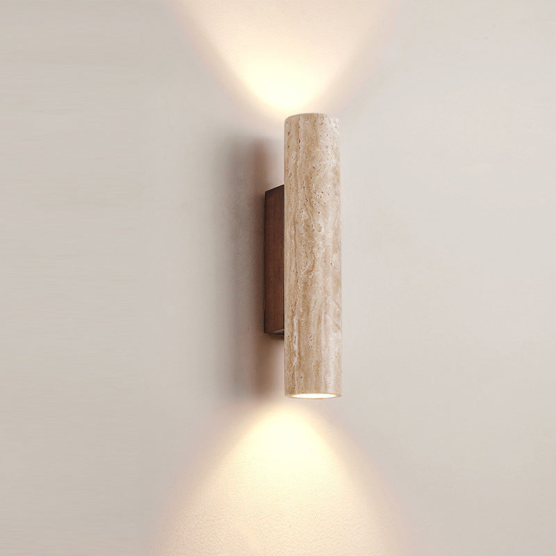 Cylindrical travertine wall sconce casting light above and below its natural stone shade