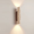Cylindrical travertine wall sconce casting light above and below its natural stone shade