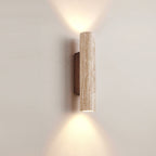 Cylindrical travertine wall sconce casting light above and below its natural stone shade