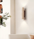 Cylindrical travertine wall sconce casting light above and below its natural stone shade