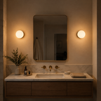 Two round wall sconce lights flank a bathroom mirror above a dark vanity.
