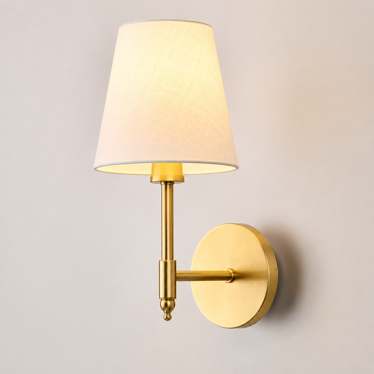 Gold wall sconce with white fabric shade displayed against a neutral background.