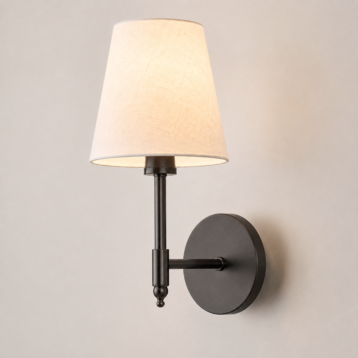 Black wall sconce with a white fabric shade, illuminated against a neutral wall.