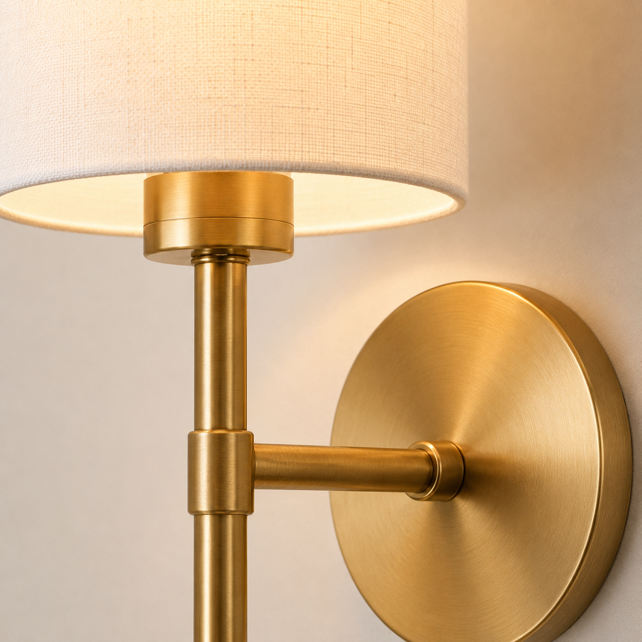 Close-up of a wall sconce showing the round mounting plate, slim stem, and cylindrical shade.