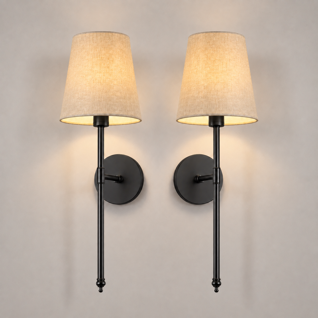 Pair of black wall sconces with white fabric shades, illuminated against a neutral wall.