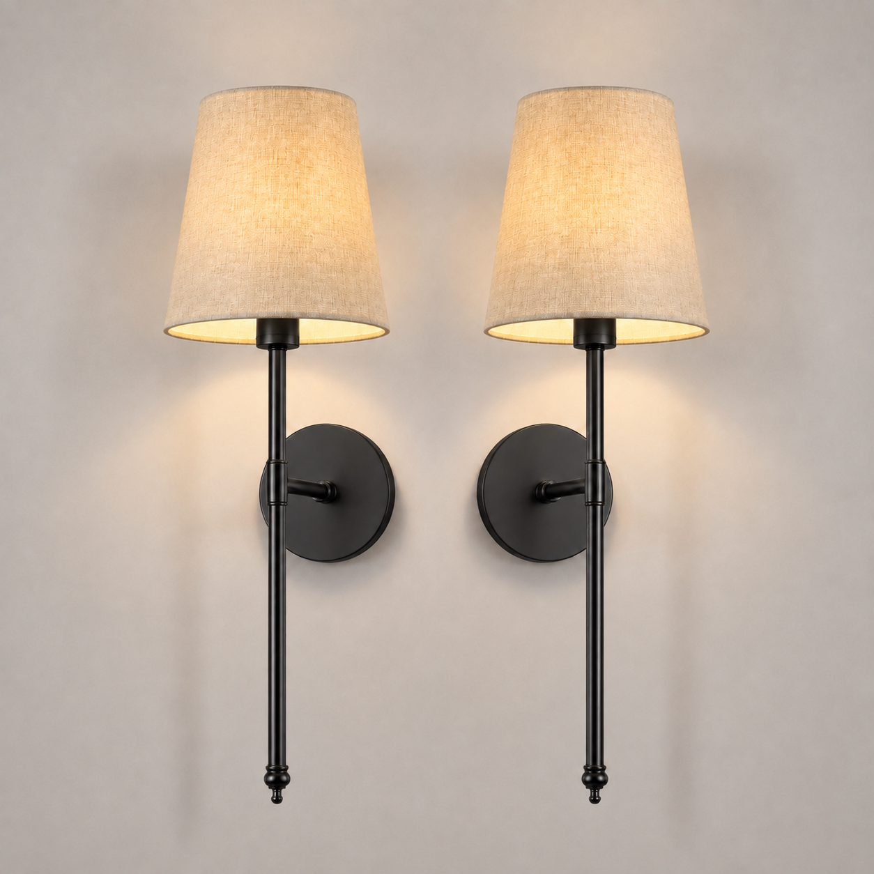 Pair of black wall sconces with white fabric shades, illuminated against a neutral wall.