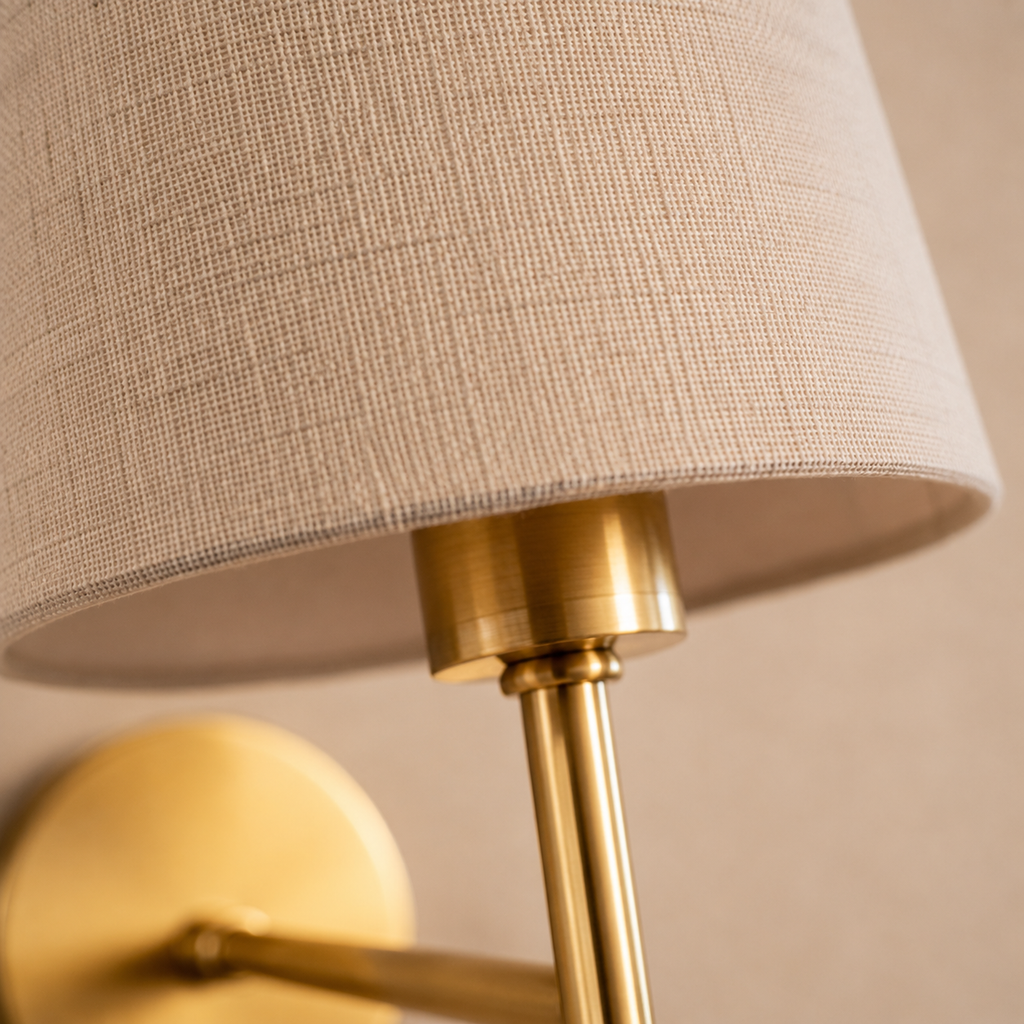 Close-up of a wall sconce showing the round mounting plate, slender arm, and tapered shade.