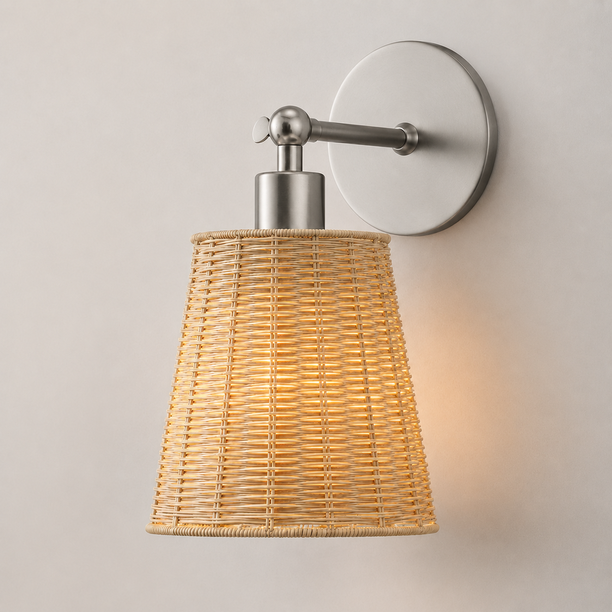 A modern wall sconce light fixture with a natural woven rattan shade and brushed nickel metal hardware, mounted on a light beige wall.