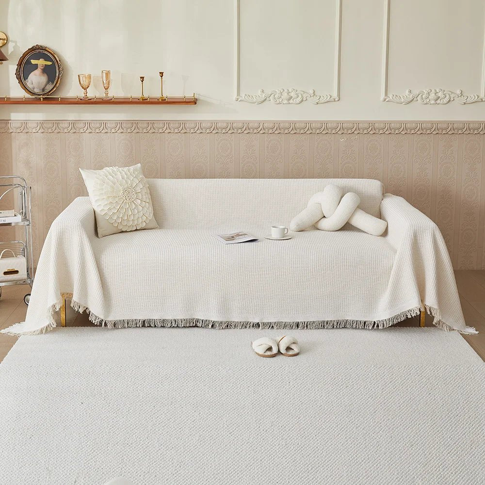 Washable sofa throw cover draped across a light-colored couch in a neutral living room.