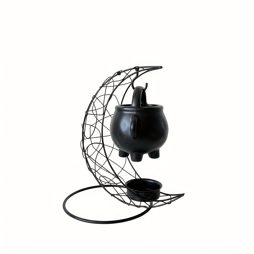 Moon shaped iron stand and hanging black cauldron against a white background.
