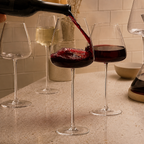 Wine glasses staged as red wine is poured beside clear and white wine stems