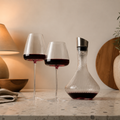 Wine glasses pair with red wine beside a ribbed crystal decanter on a stone counter