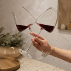 Wine glasses pair touching in a toast above a neutral kitchen counter