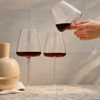 Wine glasses trio with one glass held above a warm stone counter