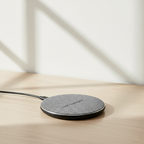 Single wireless charging pad with gray fabric surface on a desk.