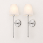 Two matching wall sconces with tapered off-white fabric shades and brushed silver metal arms, mounted side by side on a plain light wall.