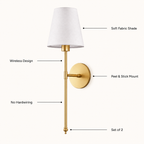 Gold wall sconce with a white fabric shade, shown with callout lines and text labels for wireless design, peel and stick mount, no hardwiring, and set of 2.