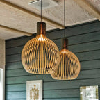 Wood pendant light pair hanging against a dark green wall