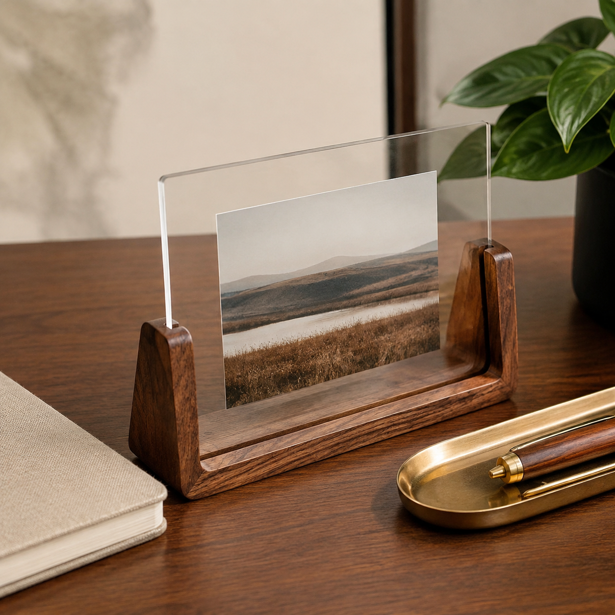 Horizontal acrylic photo frame with a walnut base on a home-office desk.