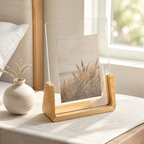 Vertical acrylic photo frame with a pale wood base beside a bedroom window.