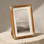 Teak portrait photo frame with brass corners on a travertine plinth