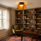 Orange ceiling light above a book-lined study.