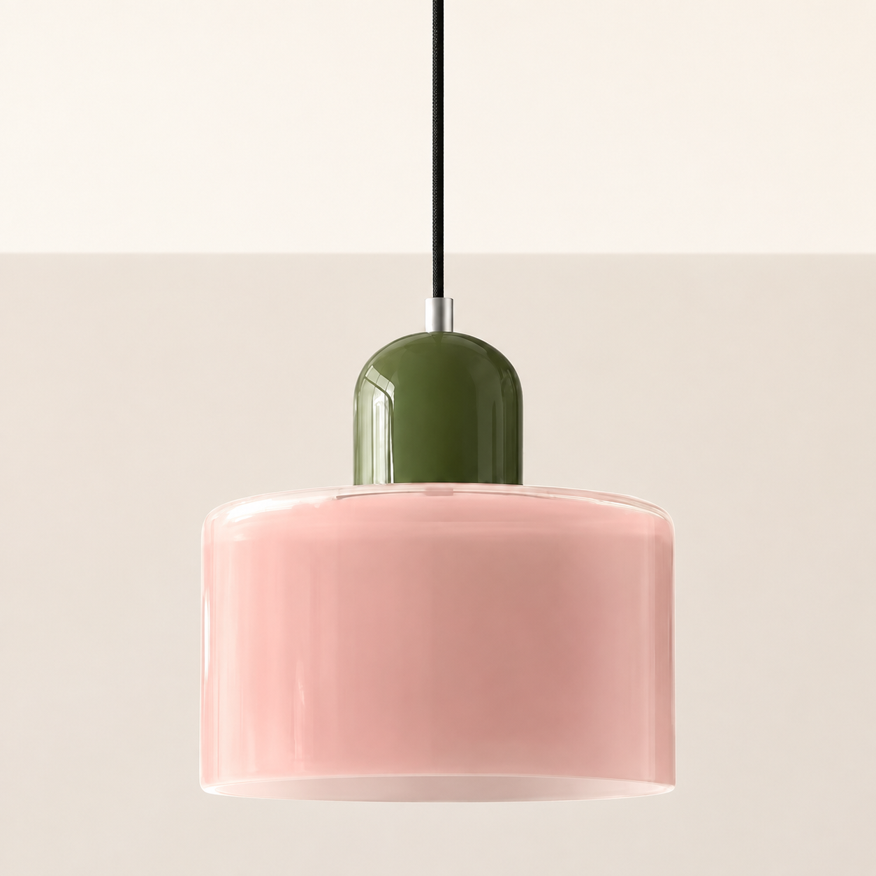 Pink circular glass pendant light with an olive cap on a warm studio wall