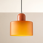 Orange circular glass pendant light glowing against a warm studio wall