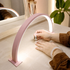 Pink crescent moon LED desk lamp glowing over a beauty workspace.