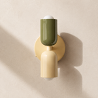 Green and beige double Scandinavian wall sconce on a pale sand wall