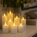 Nine flameless candles glow on a pale stone console beneath green foliage.