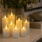 Nine flameless candles glow on a pale stone console beneath green foliage.