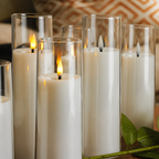 Clear flameless candles cluster closely with warm LED flames and ivory bodies.