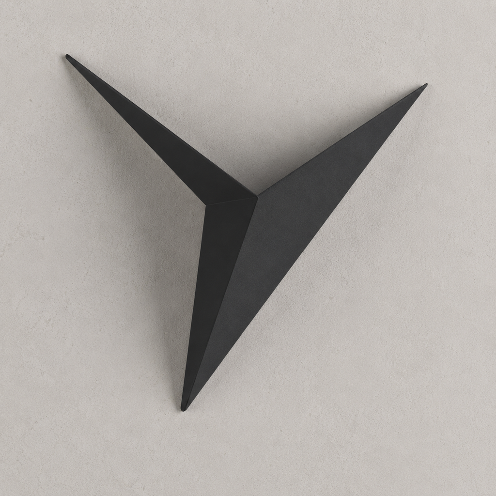 Black geometric star LED wall sconce on a warm light-gray wall