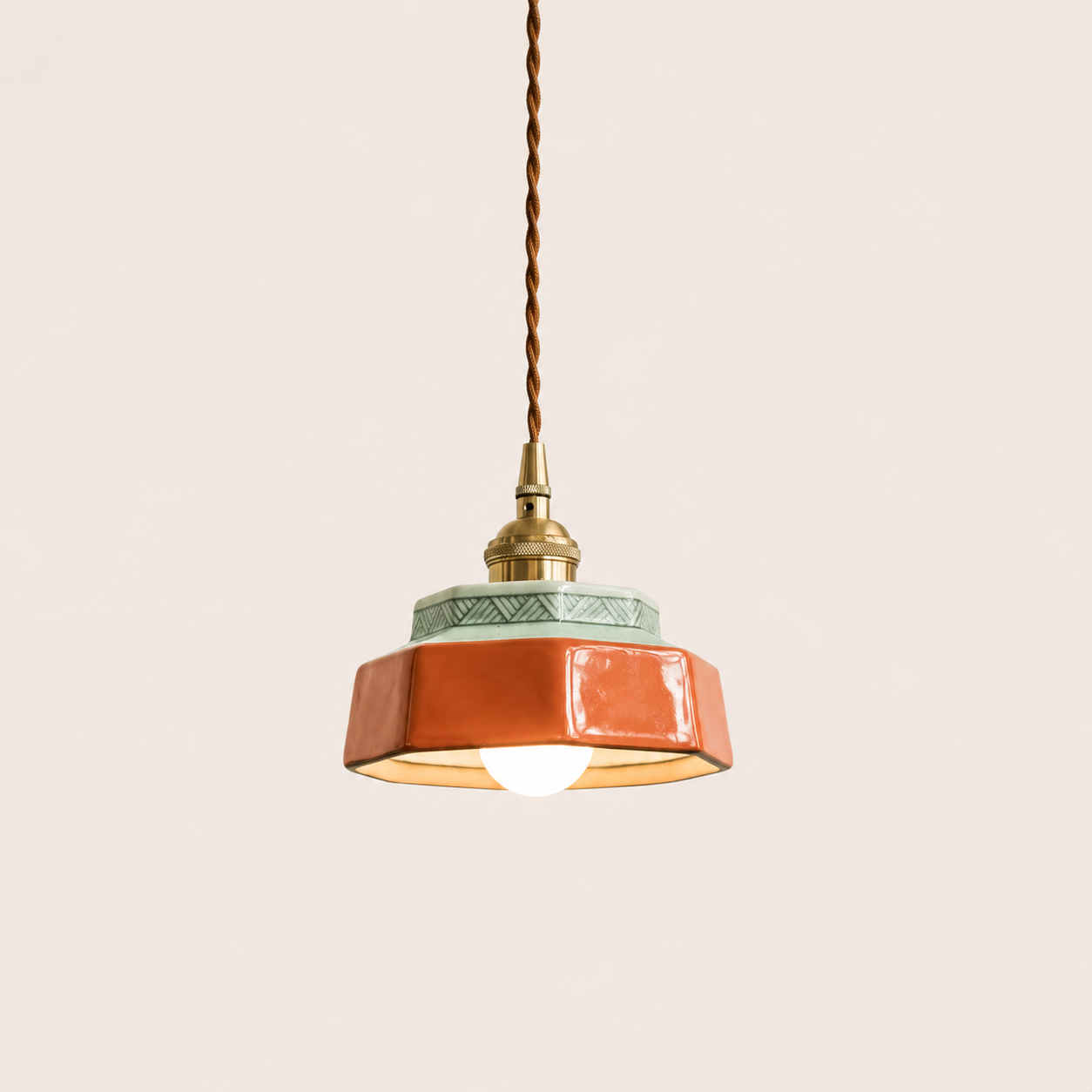 Terracotta hand-painted ceramic pendant light on an off-white studio background